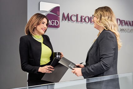 two woman in suits in front of mgd sign